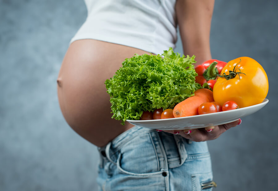 Close Up Of A Cute Pregnant Belly And Healthy Food. Pregnant Fem